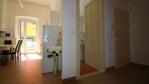 A spacious living area with a wooden floor, a dining table with chairs, a kitchen area with a refrigerator, and a door leading to another room. - Fantastic location in the centre of Porec, only 200 metres from the beach with sea views (Porec)