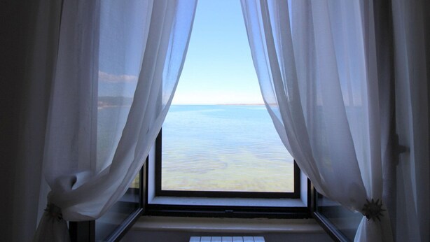 A window with sheer white curtains, offering a view of the sea. - Fantastic location in the centre of Porec, only 200 metres from the beach with sea views (Porec)