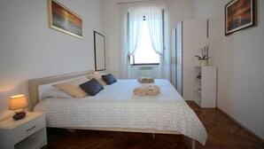 A neatly arranged bedroom with a bed, bedside table, and a window with curtains. - Fantastic location in the centre of Porec, only 200 metres from the beach with sea views (Porec)