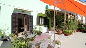 An outdoor patio with a table and chairs, surrounded by potted plants and an orange umbrella. - Fantastic location in the centre of Porec, only 200 metres from the beach with sea views (Porec)