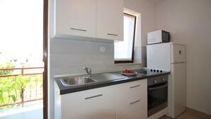 A compact kitchen with white cabinets, a stainless steel sink, a built-in oven, and a refrigerator. - Light-filled apartment just 400 metres from the beach with sea views, WiFi, air conditioning (Porec)