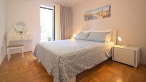 A bedroom with a bed, bedside tables, a dresser, and a painting on the wall. - Light-filled apartment just 400 metres from the beach with sea views, WiFi, air conditioning (Porec)