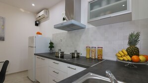 Een moderne keuken met witte kasten, een zwart aanrecht, een roestvrijstalen spoelbak en een raam boven het aanrecht.