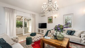 A living room with a sofa, a coffee table, a TV, and a chandelier. - Dog-friendly villa with private pool, panoramic sea view, outdoor kitchen, cot (Porec)