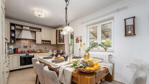 A well-lit kitchen with modern appliances, a dining table set for four, and a large window providing natural light. - Dog-friendly villa with private pool, panoramic sea view, outdoor kitchen, cot (Porec)