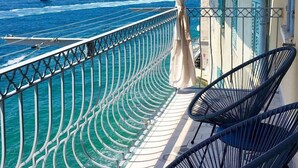 Een balkon met uitzicht op zee, met een stoel en een leuning.