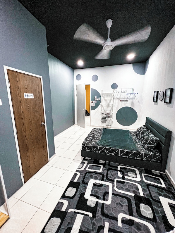 A bedroom with a bed, a ceiling fan, a door, and a wall with a circular design.