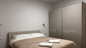 Un dormitorio con cama, armario y mesita de noche.