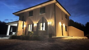 A modern two-story house with a garage, illuminated exterior lights, and a well-maintained garden. - Modern apartment in Rovinj, only 500 metres from the beach, with parking, barbecue and washing machine (Rovinj)