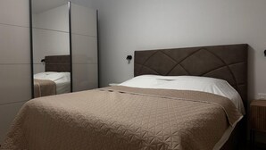 A bedroom with a bed, a mirror, and a nightstand. - Modern apartment in Rovinj, only 500 metres from the beach, with parking, barbecue and washing machine (Rovinj)