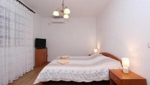 Een slaapkamer met een bed, nachtkastjes, een televisie en een plafondlamp.