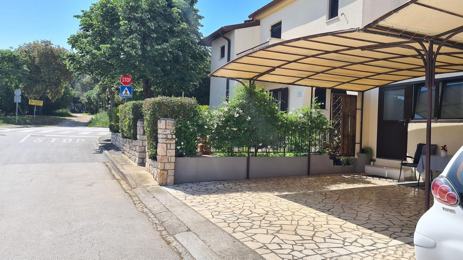 Un bâtiment doté d’un espace extérieur abrité, d’un chemin en pierre et d’un panneau de signalisation indiquant un arrêt.