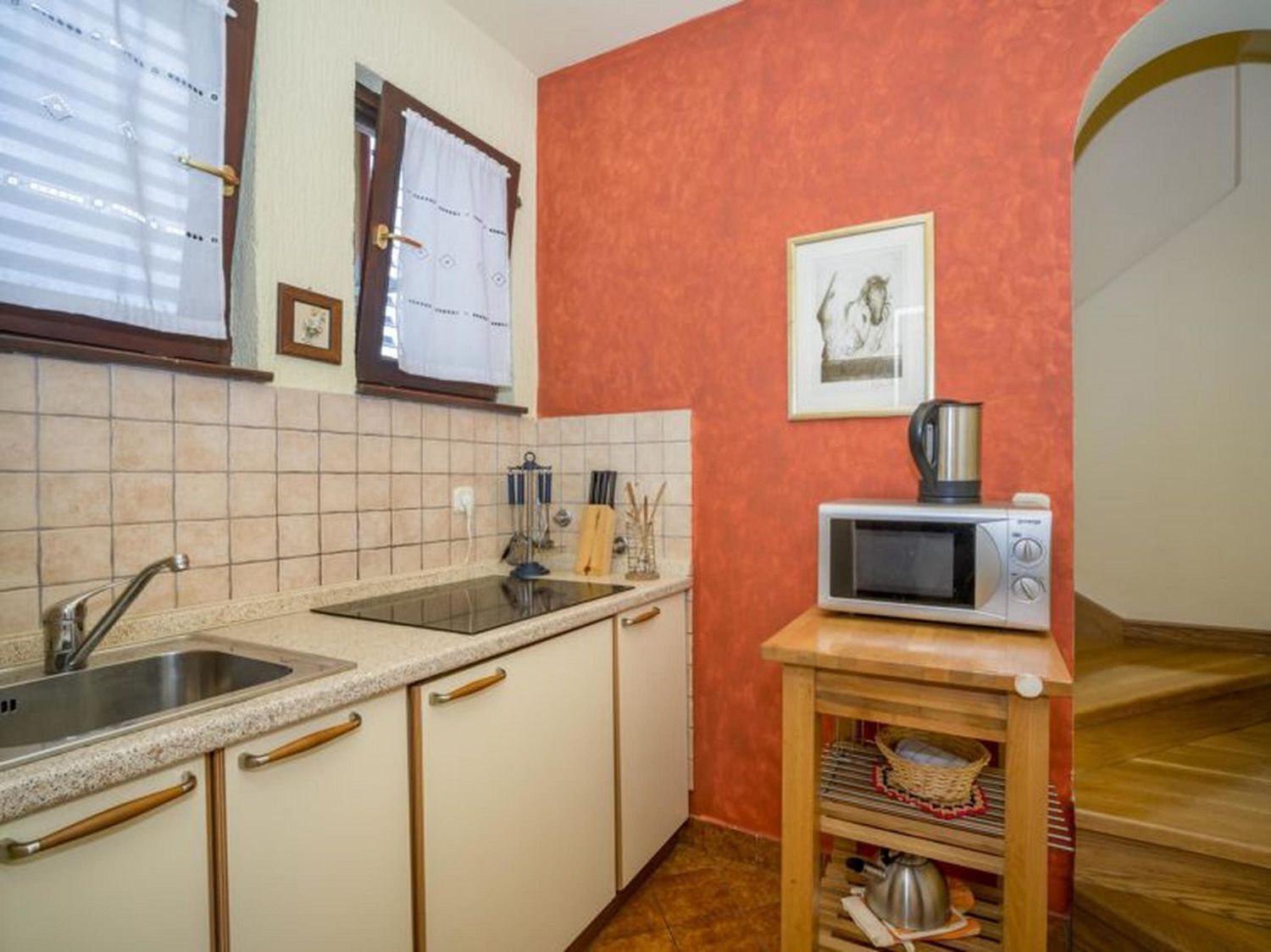 A compact kitchen with a sink, countertop, and a microwave on a small shelf.