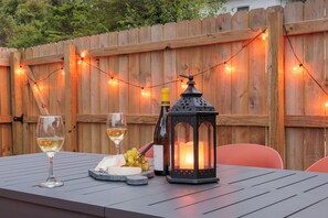 A table set with two glasses of white wine, a bottle of wine, a cheese platter, and a black lantern. - Arcade Game Room + Sleeps 12 Fast WiFi + Workspace Backyard Hangout (Dayton)