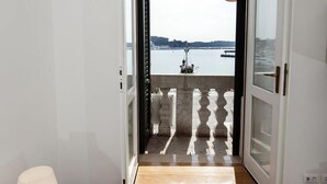 A room with a wooden floor, a white wall, and a view of a body of water through an open door. - Impressive apartment with sea view right in Rovinj, only 200 metres from the beach (Rovinj)