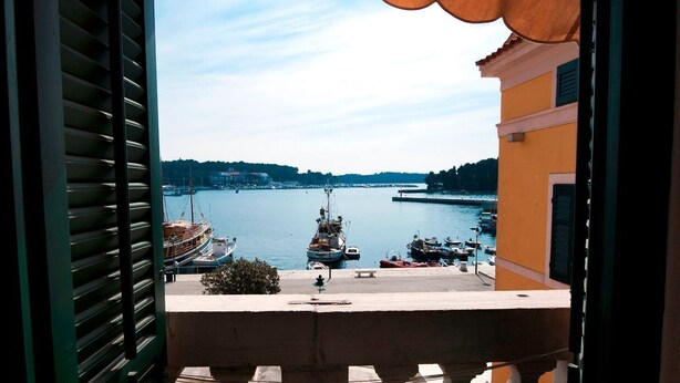A view from a balcony overlooking a harbor with boats and a distant shoreline. - Impressive apartment with sea view right in Rovinj, only 200 metres from the beach (Rovinj)