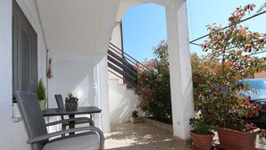 A patio with a table and chairs, potted plants, and a staircase leading to an upper level. - Modern apartment with charming terrace, private parking, air conditioning, WiFi (Rovinj)