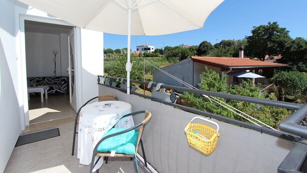 A balcony with a table and chairs, a large umbrella, and a view of the surrounding landscape. - Fantastic apartment just 400 metres from the beach – pets are welcome (Rovinj)