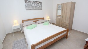 A bedroom with a wooden bed, white bedding, two bedside tables with lamps, a wardrobe, and a painting on the wall. - Fantastic apartment just 400 metres from the beach – pets are welcome (Rovinj)