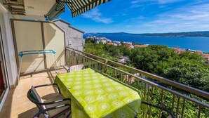 Un balcón con mesa y sillas, con vistas a un pueblo costero y al mar.