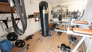 Una palestra con diverse attrezzature per esercizi, tra cui un sacco da boxe, bilancieri e una panca.