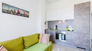 Una cucina moderna con pensili in marmo grigio, forno integrato e un divano verde con cuscini a righe.