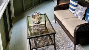 A cozy porch with a wicker sofa, a glass coffee table, and a view of the greenery outside. - Private 3BR Gem on 2.5 Wooded Acres- Close to All (Sister Bay)