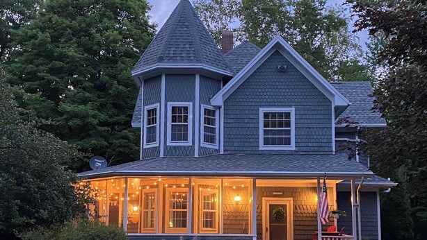A two-story house with a wrap-around porch, a turret, and a front door with an American flag. - Private 3BR Gem on 2.5 Wooded Acres- Close to All (Sister Bay)
