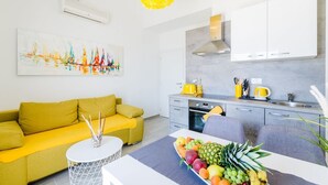 Una cocina moderna con armarios blancos, un tostador amarillo y un frutero sobre la encimera.