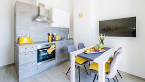 Una cocina moderna con horno integrado, una mesa de comedor con sillas y un frutero sobre la mesa.