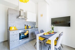 A modern kitchen with a built-in oven, a dining table with chairs, and a fruit bowl on the table. - Fantastic apartment just 600 metres from the sandy beach with gym, sea view, pool (Crikvenica)