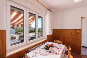 Ein Essbereich mit einem Tisch für zwei Personen, einem Fenster mit Blick auf Gebäude und Holzpaneelen.