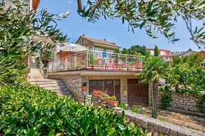 Ein Wohngebäude mit Balkon, Steinstufen und Blumentöpfen.