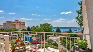 Un balcone con vista su un'area parcheggio, un edificio con tetto rosso e uno specchio d'acqua in lontananza.