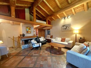 A cozy living room with a fireplace, wooden beams, and a high ceiling. - Unique chalet 6 guests, southwest terrace, Arc 1800, parking, wifi (Les Arcs 1800)