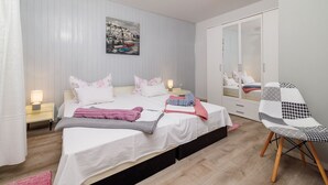 Un dormitorio con cama, mesitas de noche, una silla, armario y un cuadro en la pared.