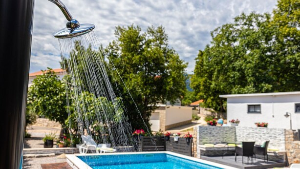 A swimming pool with a water feature, surrounded by a stone wall and greenery. - Mediterranean villa with private pool, sea view, dog-friendly, barbecue, private parking (Grižane)