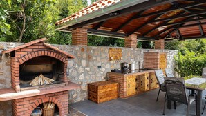 An outdoor kitchen area with a brick oven, stone walls, and a covered seating area. - Mediterranean villa with private pool, sea view, dog-friendly, barbecue, private parking (Grižane)