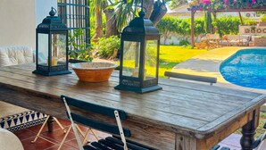 A wooden table with two lanterns and a bowl, set against a backdrop of a swimming pool and lush greenery. - Villa Alfredo in Estepona: 4 bedrooms near the beach (Estepona)