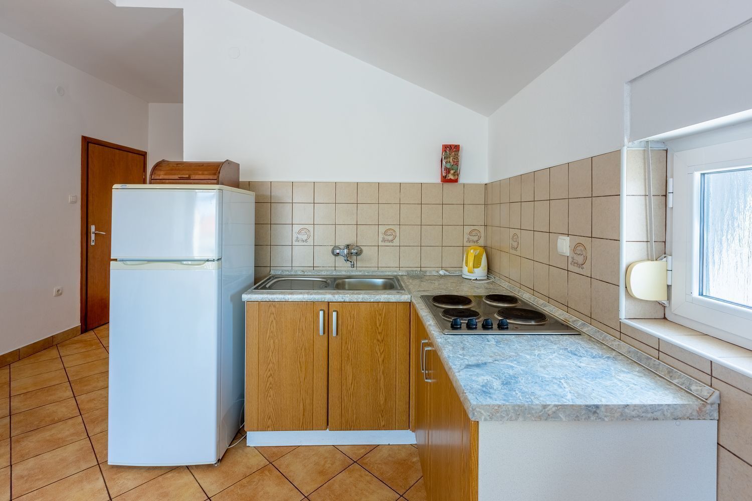 Una cucina compatta con frigorifero, mobili in legno, lavello e fornello.