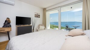 Ein Schlafzimmer mit einem großen Bett, einem Fernseher, einer Kommode und Meerblick.