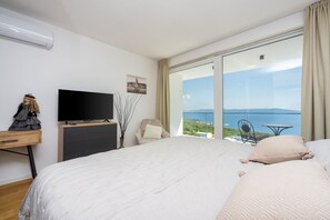 Ein Schlafzimmer mit einem großen Bett, einem Fernseher, einer Kommode und Meerblick.