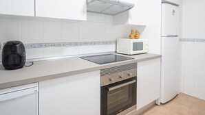Eine moderne Küche mit weißen Schränken, einem eingebauten Backofen, einer Mikrowelle und einer Kaffeemaschine.