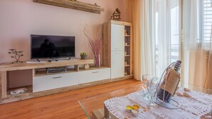 Ein Wohnzimmer mit Fernseher, Holzschrank und einem Tisch mit Kerzen.