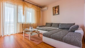 Ein modernes Wohnzimmer mit einer Couch, einem Glastisch und transparenten Vorhängen.