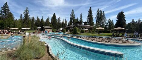 A swimming pool with multiple lanes, surrounded by trees and a grassy area.