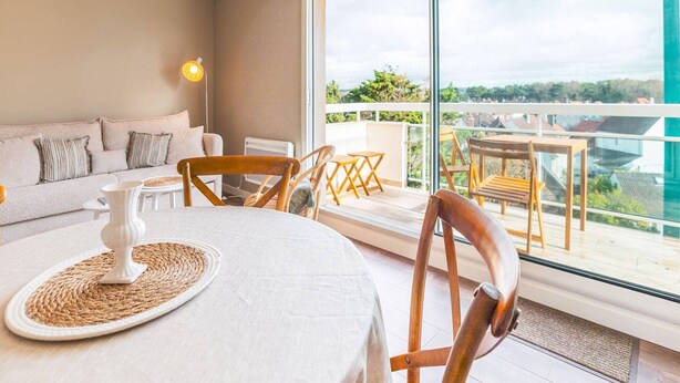 A modern living room with a sofa, a dining table with chairs, and a balcony with a view. - Comfortable Studio in Le Touquet Near Beach (Le Touquet-Paris-Plage)