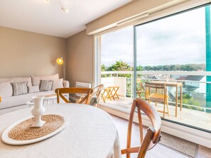 Een moderne woonkamer met een bank, een eettafel met stoelen en een balkon met uitzicht.