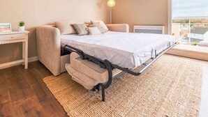 A bedroom with a bed, a bedside table, a lamp, and a view of the outside. - Comfortable Studio in Le Touquet Near Beach (Le Touquet-Paris-Plage)