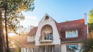 A two-story house with a prominent balcony, a large arched window, and a well-maintained lawn. - Spacious villa in quiet area with garden and Wi-Fi in Le Touquet (Le Touquet-Paris-Plage)